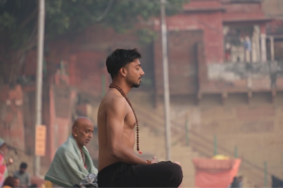 Arvin meditating at dawn with rudraksha beads by the ghats