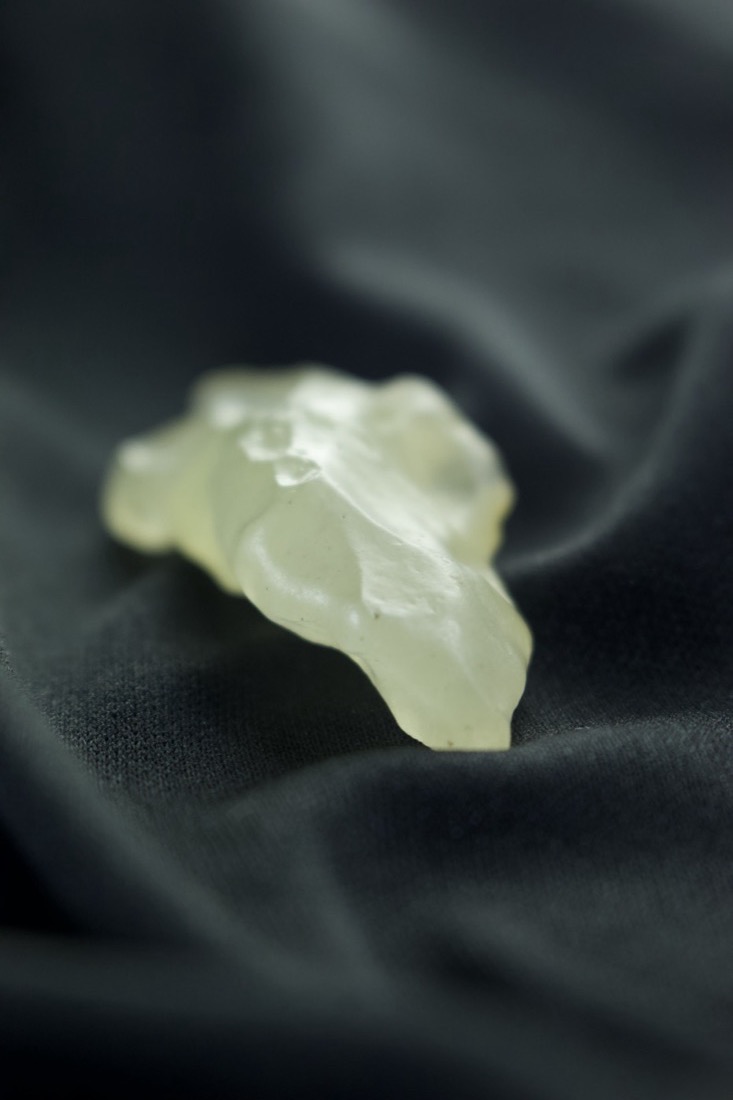 A translucent pale-yellow piece of Libyan Desert Glass on black silk