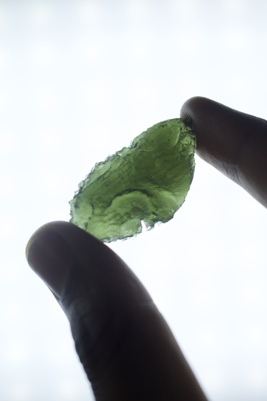 Moldavite held up to the light, glowing green